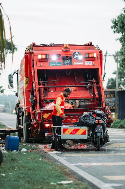 Two open-top blue waste containers filled with stacked black rubber tires, with the tires arranged in neat, overlapping rows and varying slightly in size and tread pattern. The container on the left, 
